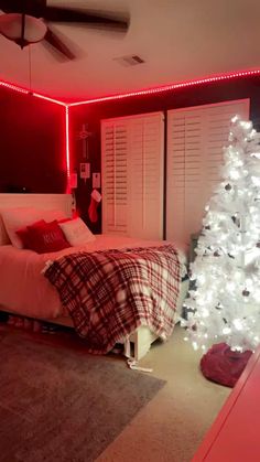 a bedroom decorated for christmas with a white tree in the corner and red lights on the ceiling