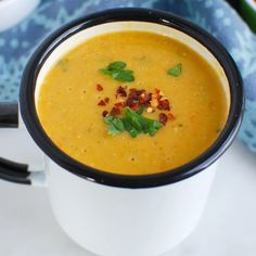 a white cup filled with soup on top of a table