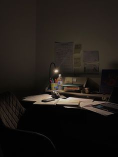 a desk with a laptop, lamp and papers on it in the dark night time