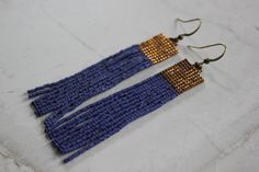 two pairs of blue and gold beaded earrings on a white surface with black beads