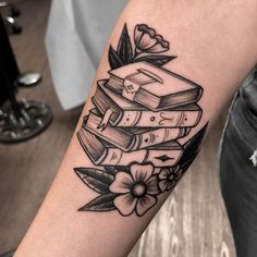 a tattoo with books and flowers on the arm