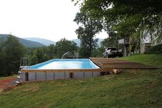 an above ground swimming pool in the middle of a field with mountains in the background