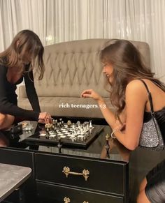 two women playing chess in front of a couch