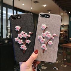 two iphone cases with flowers on them, one is pink and the other is grey