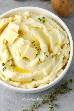 mashed potatoes with butter and parsley in a white bowl on a gray surface