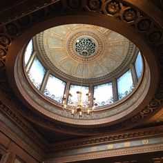 an ornate ceiling with chandelier and round glass window in the top part of it