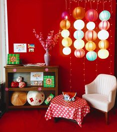 a living room with red walls and paper lanterns hanging from the ceiling over a table