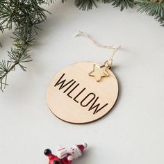 a wooden ornament with the word willow on it next to a christmas tree