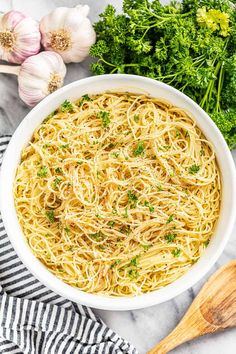 a white bowl filled with pasta and parsley next to garlic, broccoli