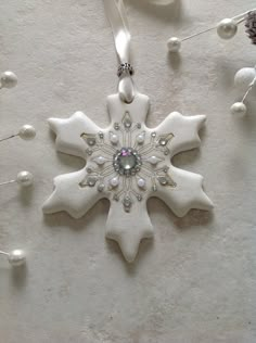 a white snowflake ornament hanging from a string on a wall next to other ornaments