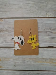 a pair of earrings made out of perler beads on top of a piece of paper