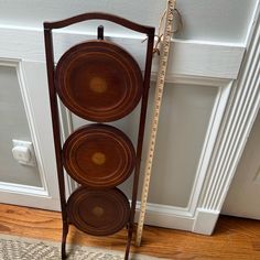 three wooden plates are stacked on a stand next to a door with a measuring tape