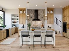 a large kitchen with wooden cabinets and white counter tops, black bar stools, and an island in the middle