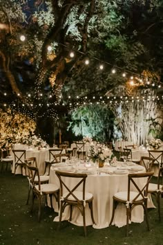 the tables are set up for an outdoor dinner under the trees with lights strung overhead