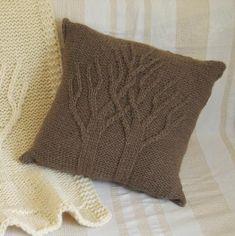 two knitted pillows sitting next to each other on a bed