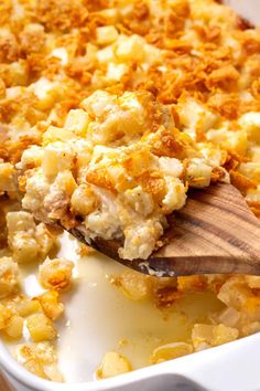 a casserole dish with macaroni and cheese being scooped from the casserole