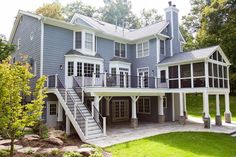 a large gray house with stairs leading up to the second story and covered porch area