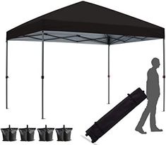 a man is walking under a black tent with six bags underneath it and five cups in front of him