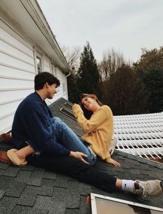 two people sitting on the roof of a house