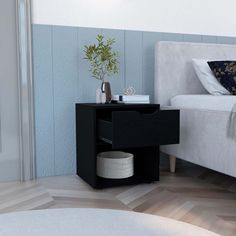 a white bed sitting next to a black night stand on top of a wooden floor