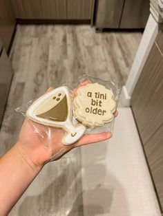 a person holding two cookies in their hand with the words a tiny bit older on them