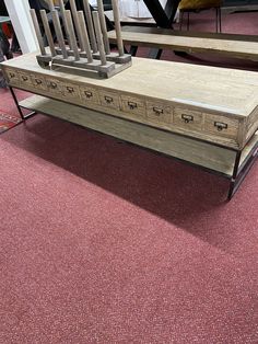 a wooden table with drawers on it in a room filled with chairs and other furniture