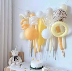 balloons and streamers are hanging on the wall next to a table with a cake