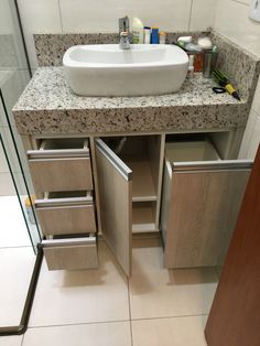 a bathroom sink sitting under a mirror next to a counter top with drawers underneath it