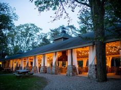 the outside of a restaurant at night with lights on and covered in white drapes