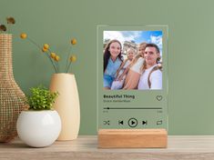 an audio player sitting on top of a wooden table next to a vase with flowers