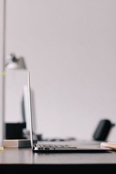 a black and white photo of a laptop on a desk in front of a lamp