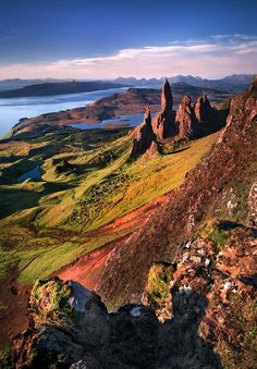 the mountains are covered in green grass and brown rocks, with blue water on each side