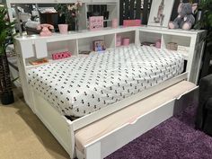 a white bed with drawers underneath it in a room