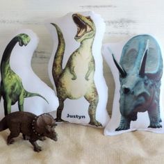 three pillows with dinosaurs on them sitting next to each other