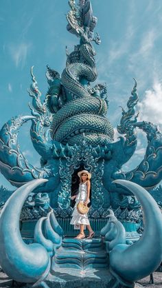 a woman standing in front of a blue dragon statue