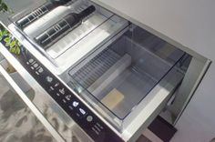 an open refrigerator sitting on top of a checkerboard floor next to a potted plant