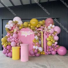 a pink and yellow birthday decoration with balloons