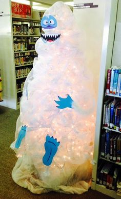 a white christmas tree with blue monsters on it in the middle of a book store