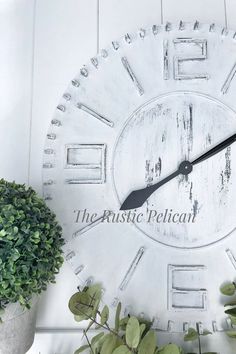 a white clock sitting next to a potted plant