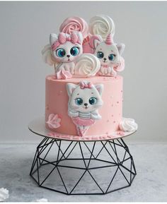 there is a pink cake with cats on it and blue eyes in the top tier