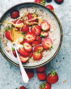 a bowl of oatmeal with strawberries on the side