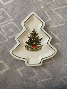 a christmas tree shaped serving dish on a gray tablecloth with white and green trim