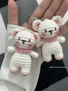 two crocheted teddy bears are being held by someone's hand on a checkered table cloth