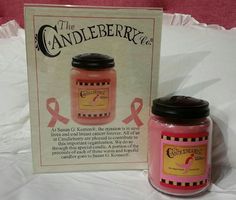 a pink candle with a black lid next to a book about the candleberry company