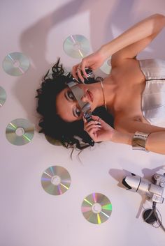 a woman is talking on her cell phone while surrounded by cd's and cds