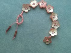 a bracelet made out of buttons and string on a blue surface with a pink cord