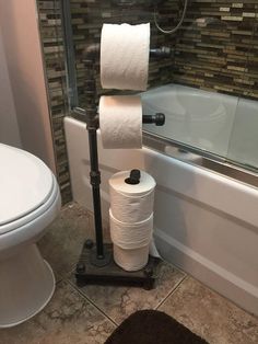 two rolls of toilet paper are stacked on a stand next to a bathtub