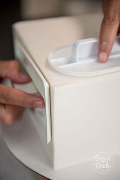 a close up of a person pressing buttons on a white box with the lid open