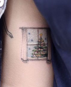 a small christmas tree is on the side of a woman's right arm,