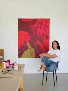 a woman sitting on a chair in front of a painting